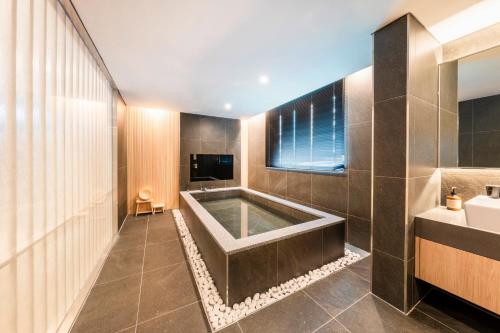 a bathroom with a bath tub and a sink at Hotel Foret The Spa in Busan