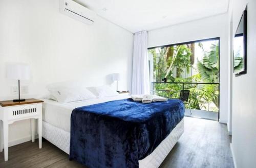 a white bedroom with a bed and a large window at Pousada Armação de Camburi in Camburi