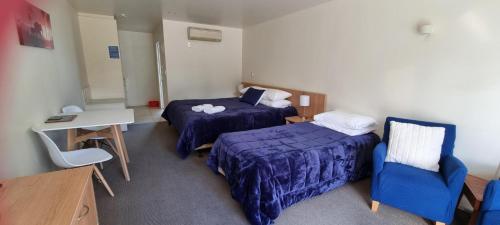 a room with two beds and a table and a desk at Methven Motel & Apartments in Methven