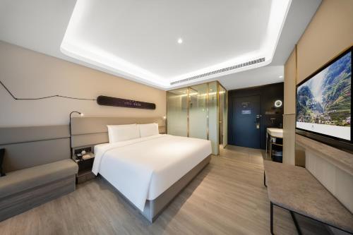 a bedroom with a white bed and a flat screen tv at Atour Light Hotel Chengdu Dujiangyan in Dujiangyan