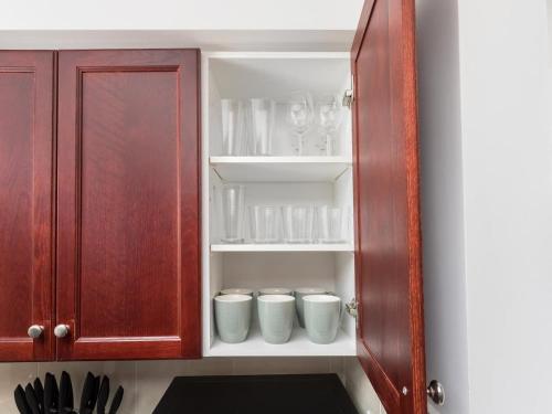 a cupboard with cups and mugs in it at Luxury Downtown Retreat Condo in Prime Location in Toronto