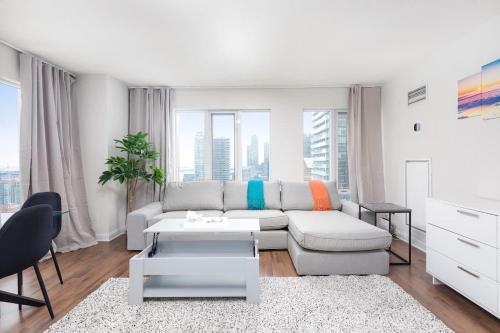 a white living room with a couch and a table at Luxury Downtown Retreat Condo in Prime Location in Toronto