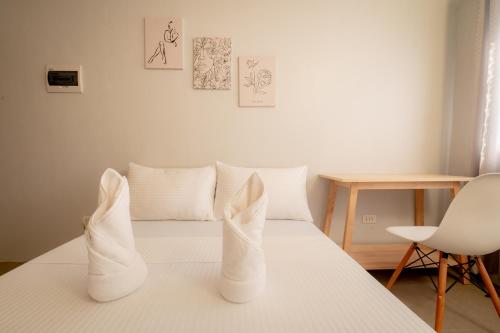 a white bed with white pillows and a chair at Cozypod Rentals in Sagcahan