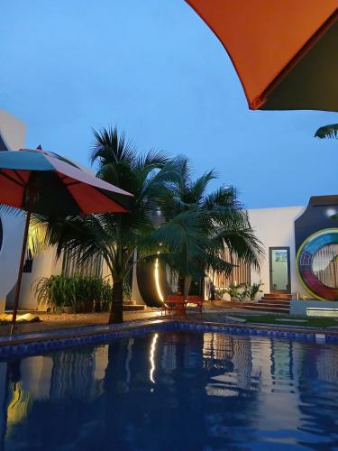 a swimming pool with palm trees next to a building at paparazzi homestay in Xuyên Mộc