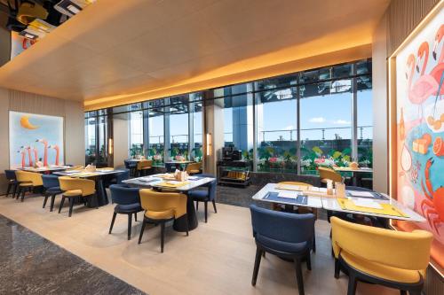 a restaurant with tables and chairs and large windows at voco Zhoushan Putuo by IHG in Zhoushan