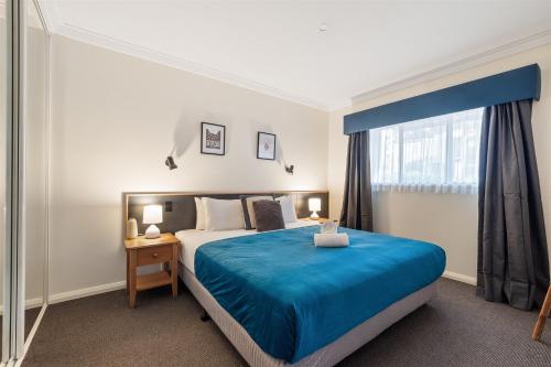 Un dormitorio con una cama azul y una ventana. en TreeTops Margaret River, en Margaret River Town