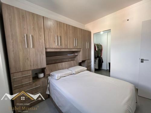 a bedroom with a white bed and wooden cabinets at Apartamento Festa do Peão Barretos in Barretos