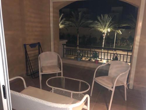2 chaises et une table sur un balcon avec des palmiers dans l'établissement Villa 4 Bedrooms Marassi Verdi, à El Alamein