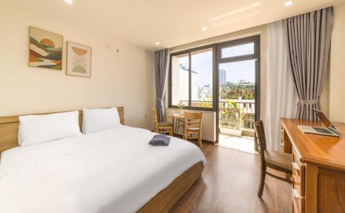 a hotel room with a bed and a desk and a window at Sóng homestay 4 - The spacious house - In the Prime location in Da Nang