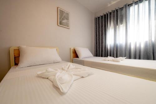 two beds in a bedroom with white sheets and a window at Cozypod Rentals in Sagcahan