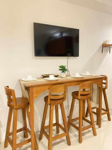 a wooden table with four chairs and a television on a wall at Kozzy Loft Sitari Condominium in Bacolod
