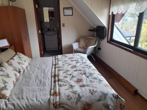 a bedroom with a bed and a chair and a window at Hostal Möller in Villarrica