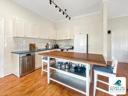 a kitchen with white cabinets and a wooden counter top at Surf Beach Remote Retreat - Linen Included in Surf Beach