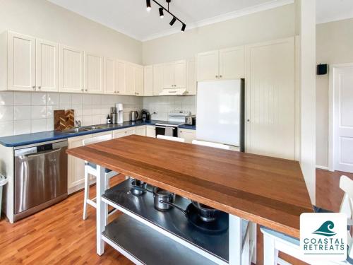 a kitchen with white cabinets and a wooden counter top at Surf Beach Remote Retreat - Linen Included in Surf Beach
