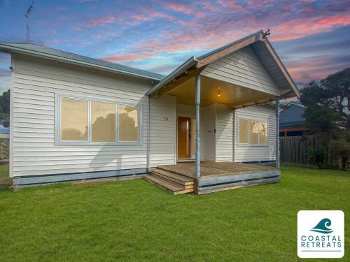 a small white house with a porch on a lawn at Surf Beach Remote Retreat - Linen Included in Surf Beach