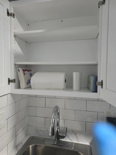 a kitchen with a sink and a shelf with towels at Newly built Studio Close to NYC and EWR in Irvington