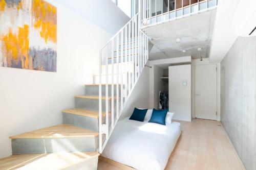 a white staircase with a white couch and blue pillows at PASEO ichigayadaimachi I in Tokyo