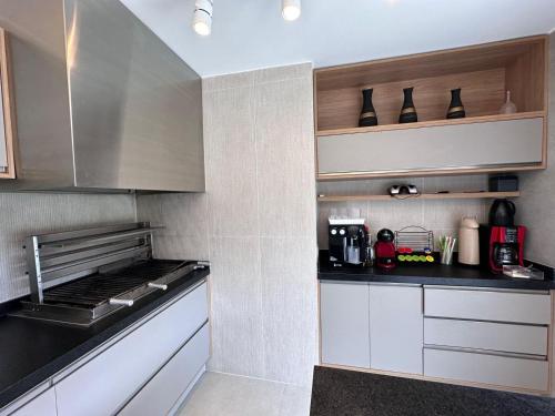 a kitchen with white cabinets and black counter tops at Villa Entre Verdes in Riviera de São Lourenço