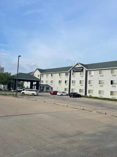 a large white building with cars parked in a parking lot at New Victorian Inn & Suites Lincoln in Lincoln