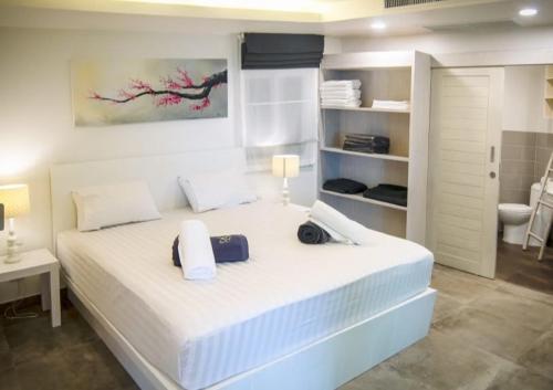 a white bedroom with a large white bed with two bags on it at Karon beach Stylish large 2BR with Sea View in Ban Karon
