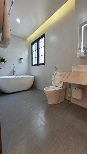 a bathroom with a tub and a toilet and a sink at Anh Thư Villa Hồ Tràm in Xuyên Mộc