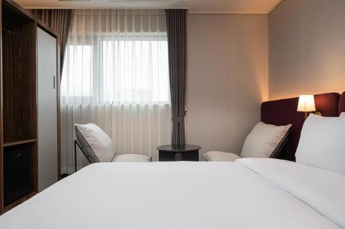 a hotel room with a bed and two chairs and a window at Hound hotel gunsan in Gunsan