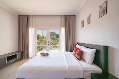 a bedroom with a large bed and a large window at Casa Raya 4BR Villa in Kuta in Kuta