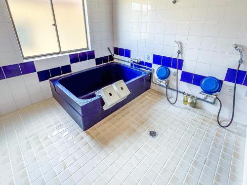 a bathroom with a blue tub and a toilet at Sea Tiger Island Inn Shodoshima in Shodoshima