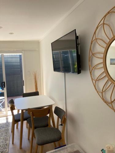 a dining room with a table and a tv on a wall at Maraetai Beachfront bliss one bedroom apartment in Maraetai