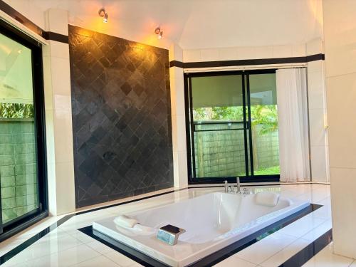 een grote witte badkuip in een badkamer met ramen bij Paradise House in Thai Muang