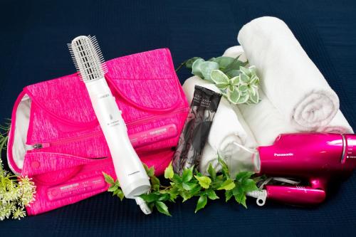 a pink bag with a bottle of lipstick and towels at BON Condo Namba Nipponbashi in Osaka