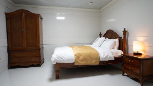 a bedroom with a bed and a cabinet and a nightstand at Taebaek Hotel in Taebaek
