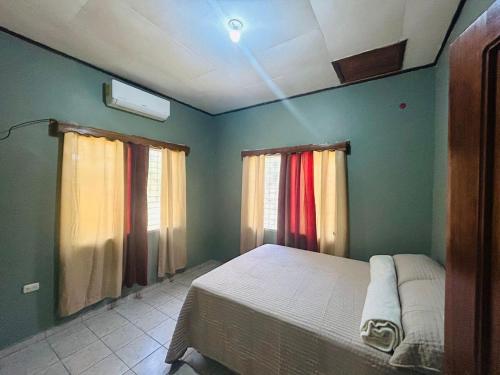 a bedroom with a bed and two windows at Cozy house, close to the beach in Tulian Campo in Tulián