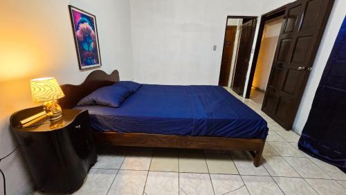 1 dormitorio con 1 cama con sábanas azules y lámpara en Hostal casa el calvarito, en León
