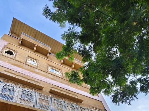 a building with a tree in front of it at Heritage Haveli Jaisalmer in Jaisalmer