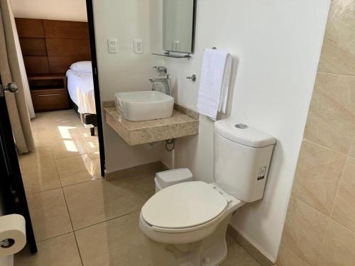 a bathroom with a white toilet and a sink at Casa Cómoda en Privada con Canchas y Alberca in Cancún