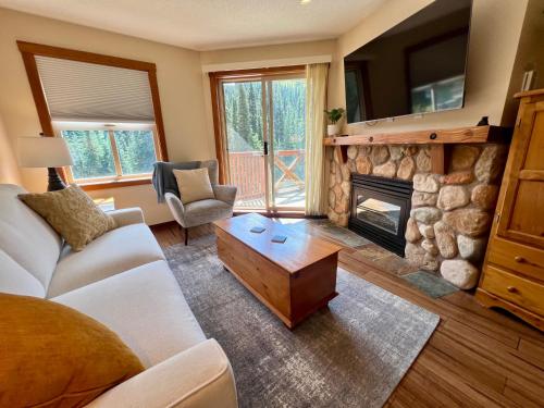 a living room with a couch and a fireplace at Main Village, Ski-in Ski-out, Hot Tub, Condo in Sun Peaks