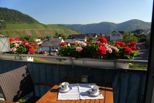 a table on a balcony with red flowers and a view at Appartement Familie Ernst in Bruttig-Fankel