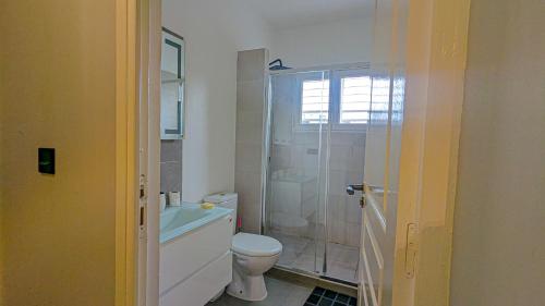 a bathroom with a toilet and a glass shower at Le Champ des Roseaux - Kotto Douala in Douala