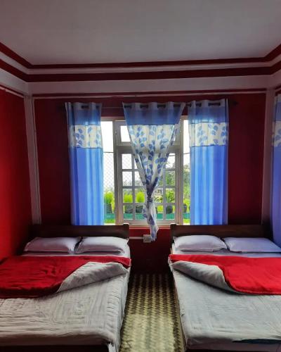 2 camas en una habitación con cortinas azules y ventana en Two Sisters, en Sonāda