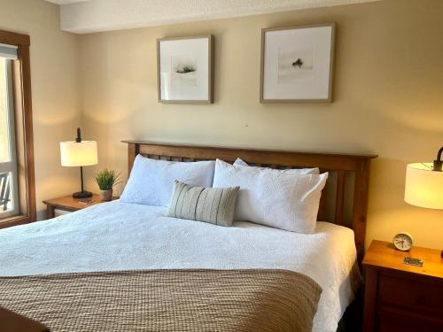 a bedroom with a bed with white sheets and two lamps at Main Village, Ski-in Ski-out, Hot Tub, Condo in Sun Peaks
