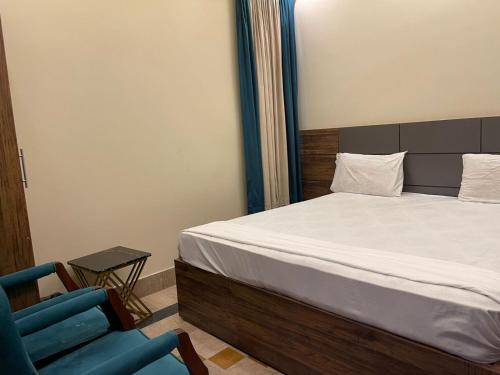 a bedroom with a bed and a blue chair at Hotel Elegant Gulshan-e-Iqbal karachi in Karachi