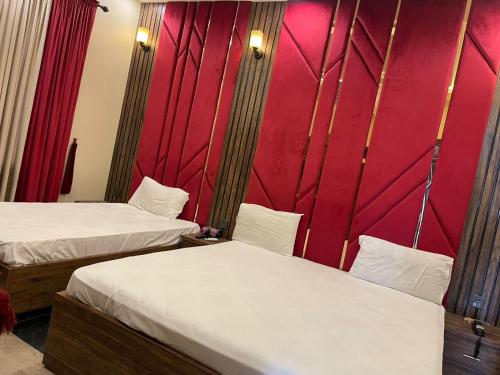 a room with two beds and a red wall at Hotel Elegant Gulshan-e-Iqbal karachi in Karachi