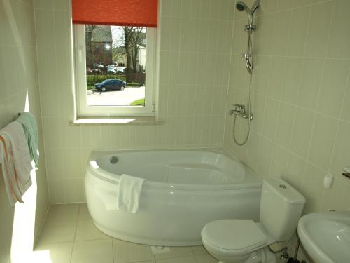 uma casa de banho com uma banheira, um WC e uma janela. em Tukuma Ledus Halle em Tukums