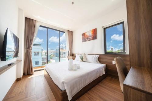 a bedroom with a bed and a tv and windows at BRIO Urbano Apartment in Danang