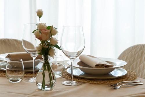 a table with two wine glasses and a vase with flowers at Hotel Monti in Lamporecchio