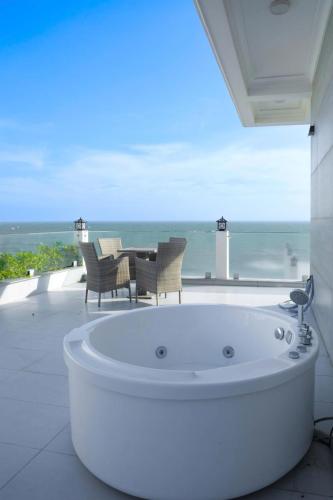 a bath tub in a room with a view of the ocean at Bay View Beach Villas Mũi Né in Ấp Khánh Phước (1)