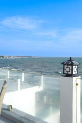 a black and white clock tower on a balcony overlooking the ocean at Bay View Beach Villas Mũi Né in Ấp Khánh Phước (1)