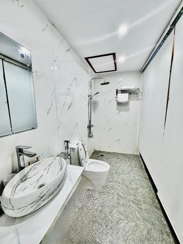 a white bathroom with a toilet and a sink at Green Valley Homestay - Thung Lũng Xanh in Nguyên Ngoại