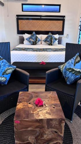 a bedroom with a bed and a wooden table with two chairs at Bulabard Villa in Nayawa